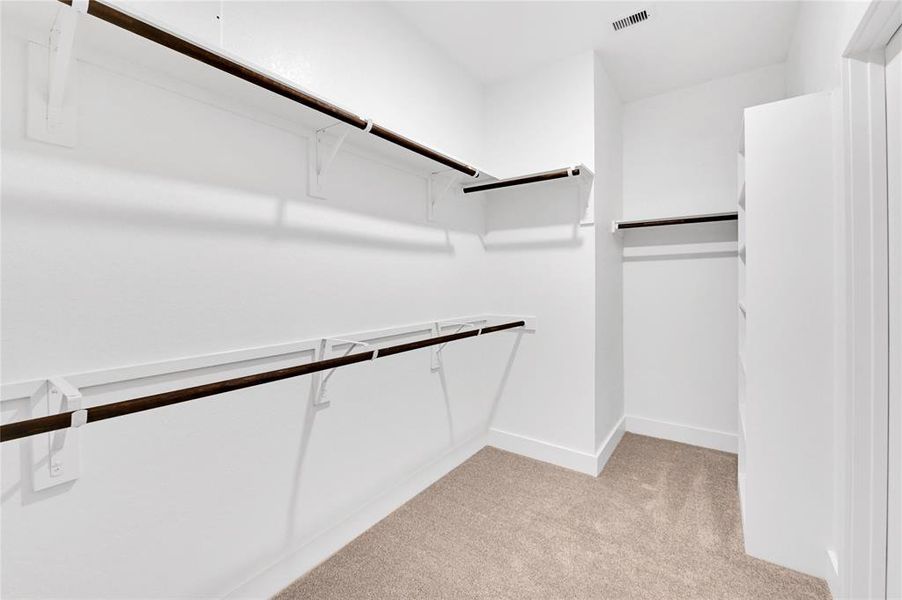 Your spacious primary closet comes complete with dual hanging rods, plush carpeting, and built-in accessory shelving.