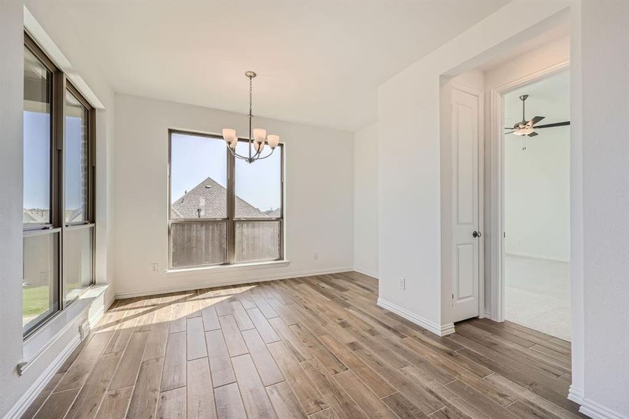 Unfurnished dining area featuring hardwood / wood-style flooring, ceiling fan with notable chandelier, and a wealth of natural light