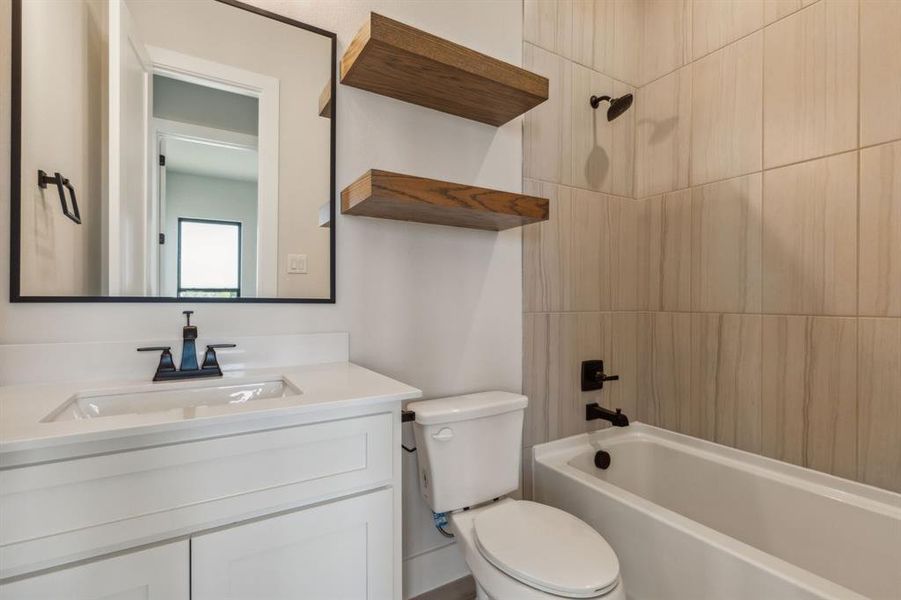 Full bathroom with tiled shower / bath, vanity, and toilet