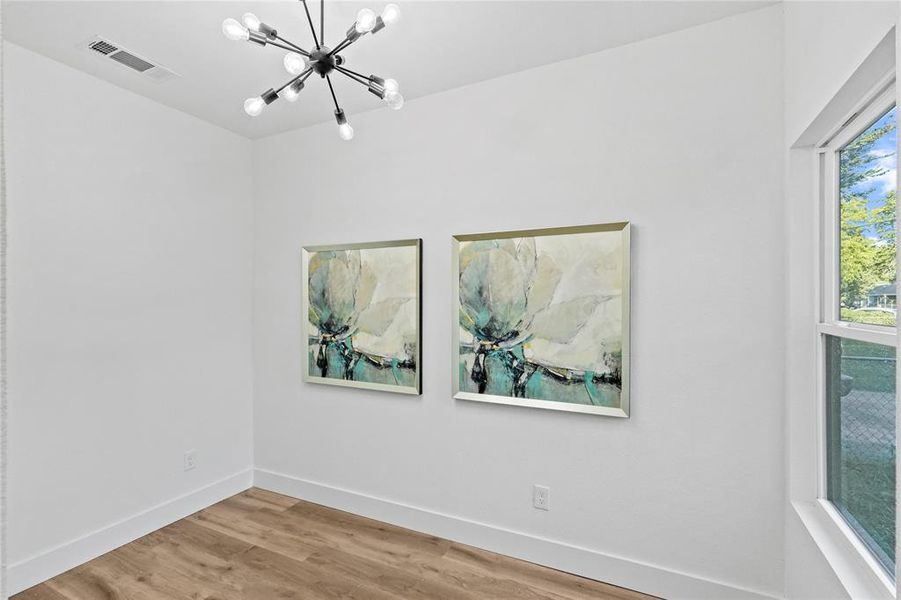 Spare room featuring a notable chandelier and hardwood / wood-style flooring