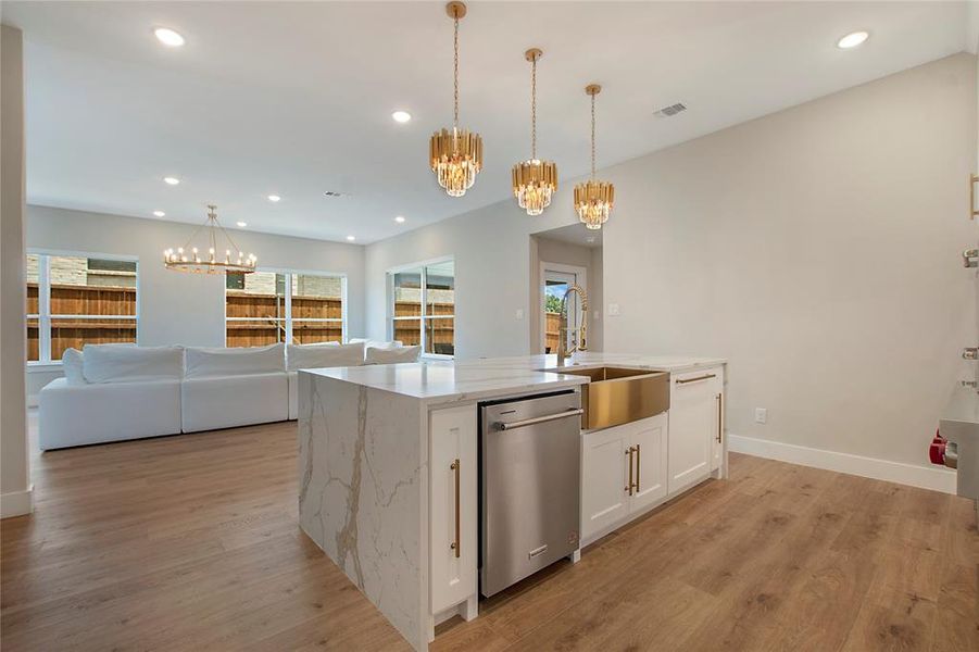 Kitchen featuring light hardwood / wood-style floors, a center island with sink, white cabinets, sink, and dishwasher