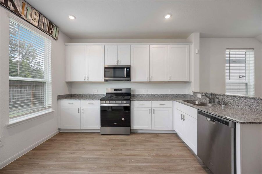 Open-concept kitchen with granite countertops and bar overlooking dining area.