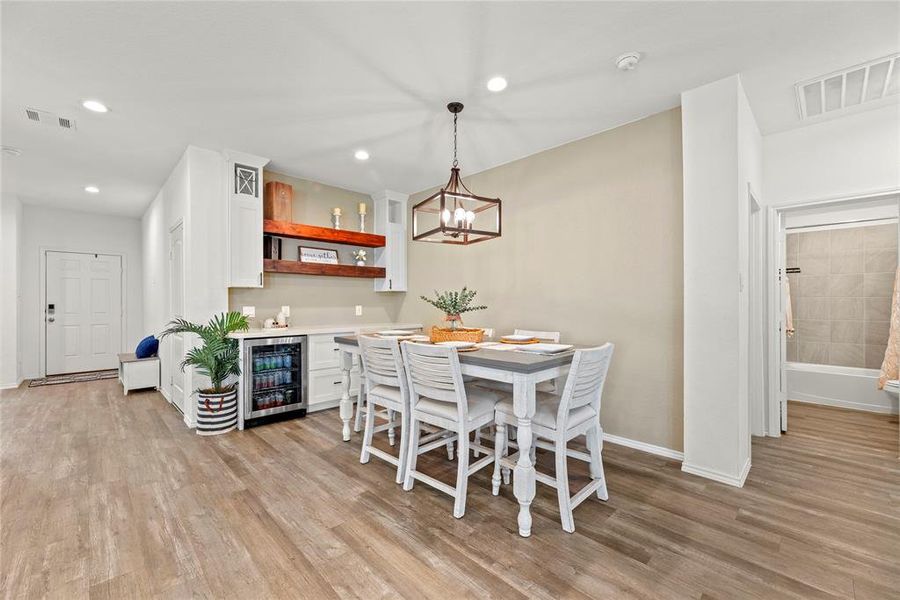 The dining area is ideal for a full-sized table and features hardwood floors, designer paint, overhead chandelier, and an additional area with coordinating counter and cabinet space.