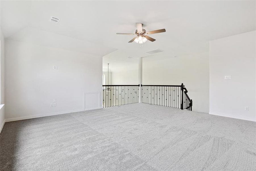 Carpeted spare room with ceiling fan and vaulted ceiling