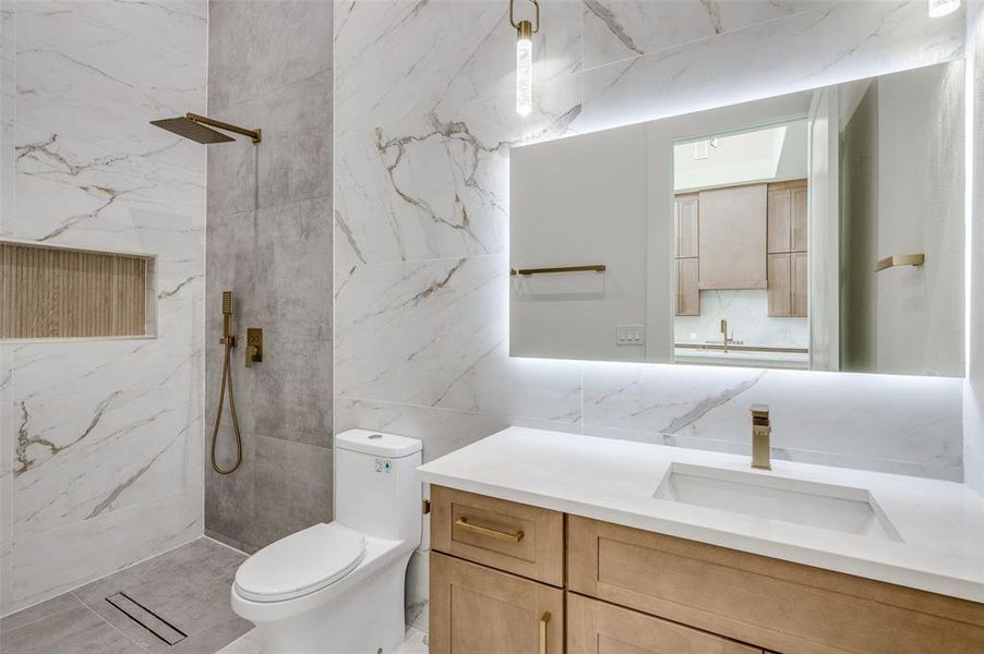 Bathroom featuring decorative backsplash, a tile shower, tile walls, toilet, and vanity