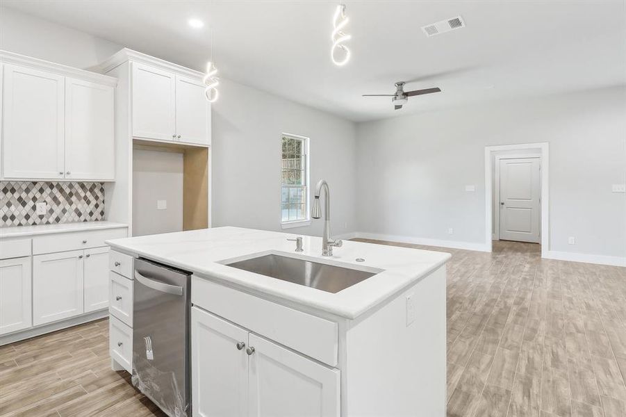 Kitchen with white cabinets, dishwasher, ceiling fan, and sink