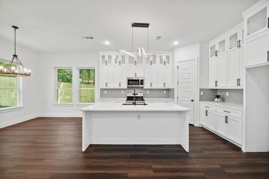 Kitchen featuring white cabinets, appliances with stainless steel finishes, and backsplash