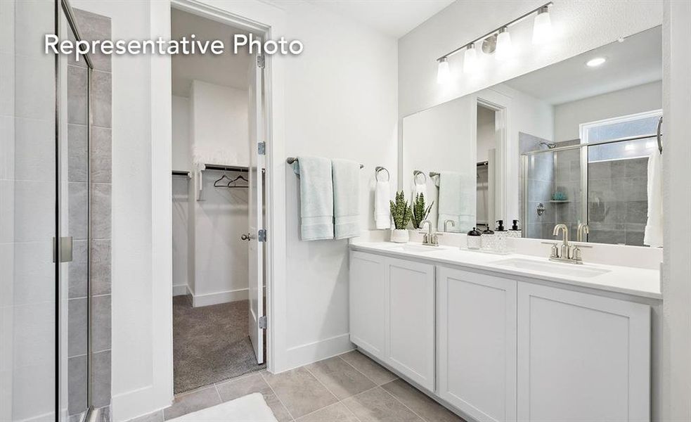 Bathroom with a shower with shower door, dual vanity, and tile patterned floors