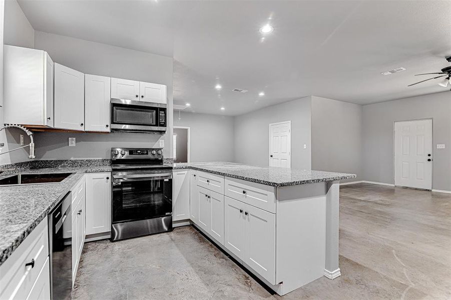 Kitchen featuring white cabinetry, ceiling fan, stainless steel appliances, sink, and kitchen peninsula