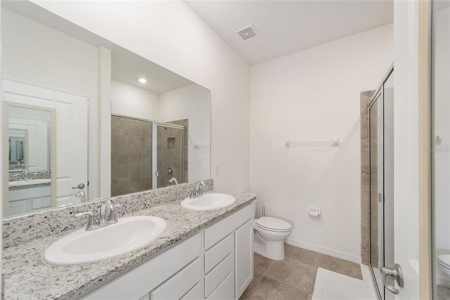 Owner's bathroom with dual sinks, large shower and granite counters