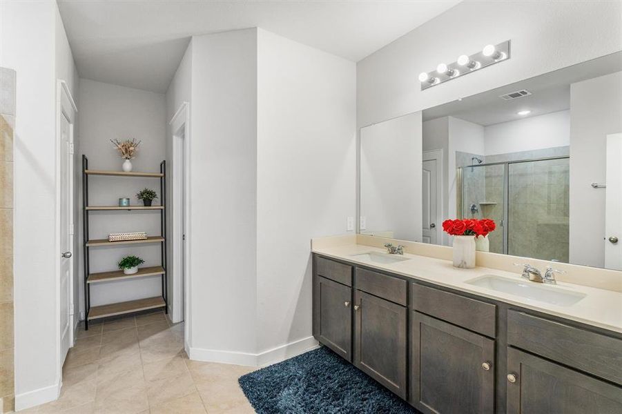 Bathroom featuring a shower with door, vanity, and tile patterned floors