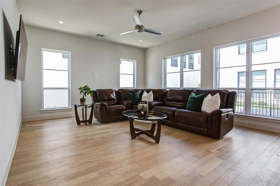 Living room with ceiling fan and light hardwood / wood-style floors