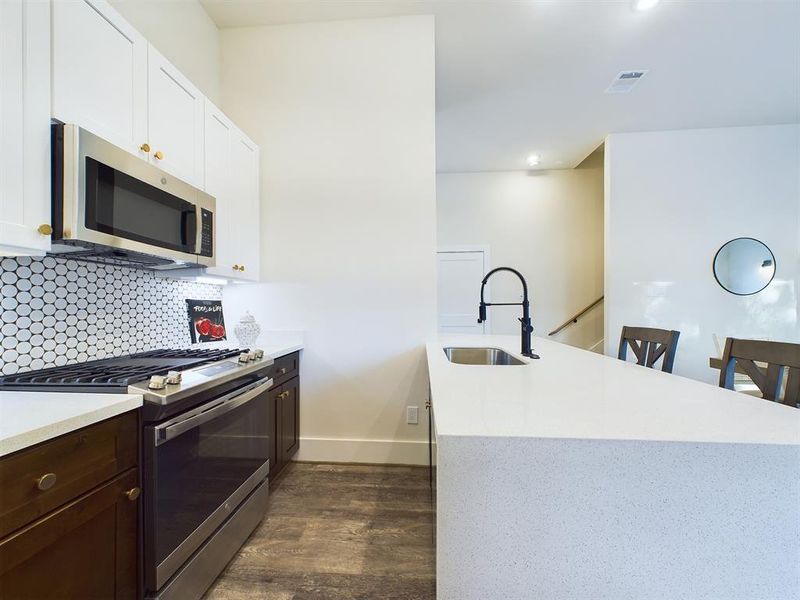 A thoughtfully selected backsplash, modern stainless steel appliances, dual-toned cabinetry, and under cabinet lighting are just SOME of the design aspects that this gorgeous kitchen has to offer! *All interior photos are from the model home: 2915 Paul Quinn.*