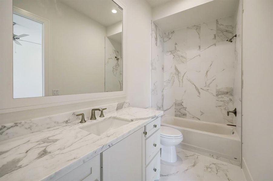 The luxurious ensuite bath tied to this secondary bedroom features marble floor, marble countertop and shower/tub surround with marble to the ceiling! Notice the framed mirror!