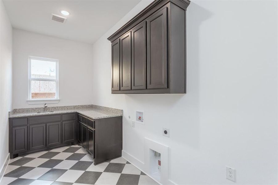 Clothes washing area with cabinets, hookup for an electric dryer, sink, and hookup for a washing machine