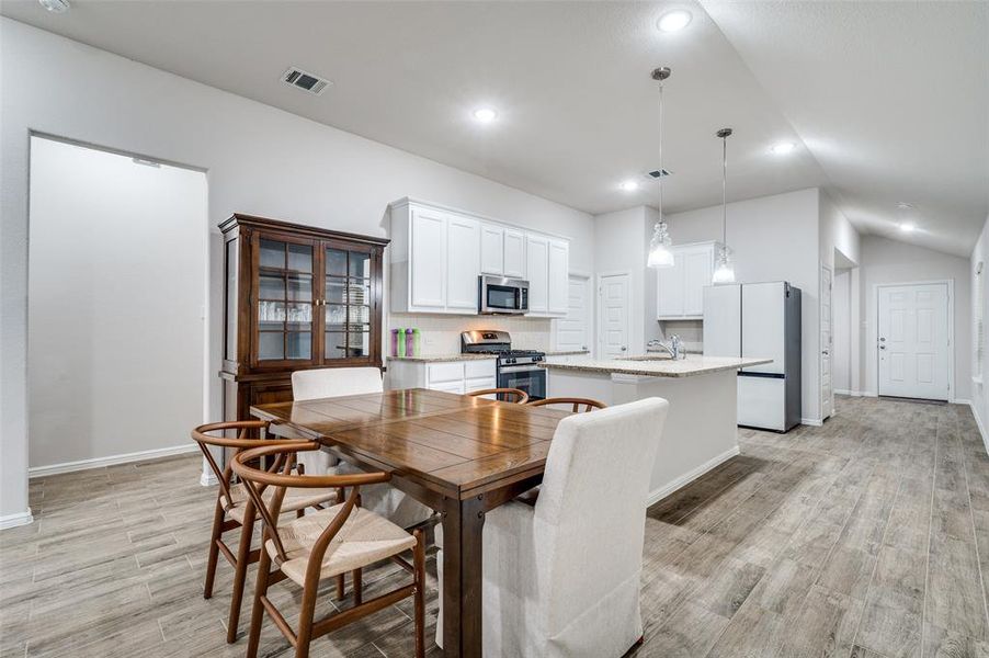 Dining space with vaulted ceiling, sink, and light hardwood / wood-style floors