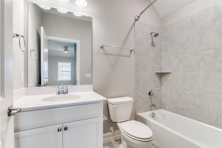 Full bathroom with vanity, toilet, ceiling fan, and tiled shower / bath