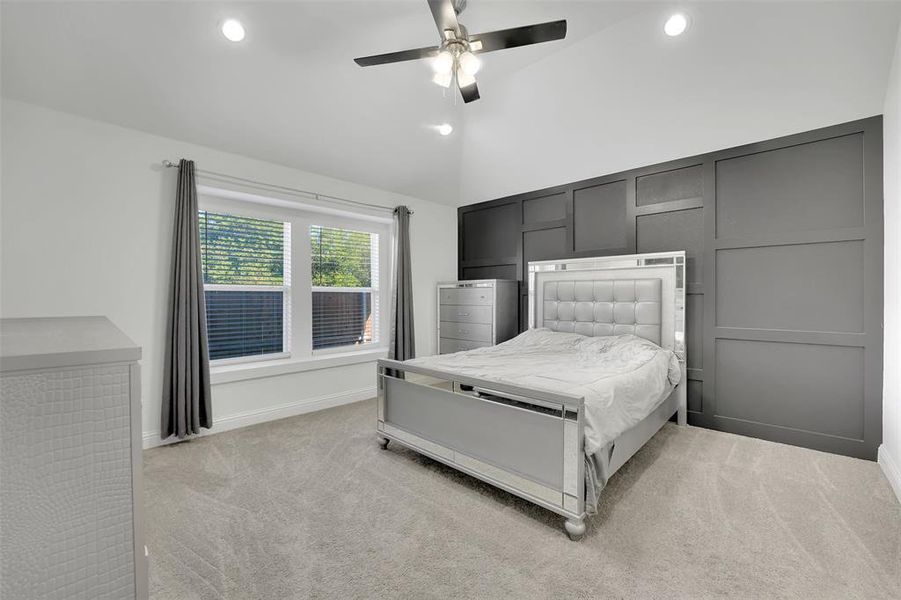 Unfurnished bedroom with light colored carpet, ceiling fan, and vaulted ceiling