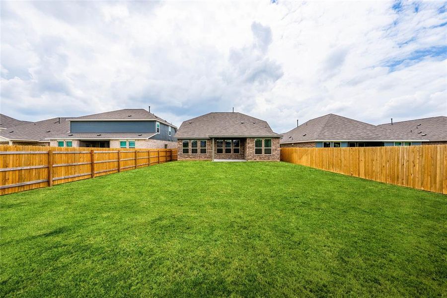 Large, lush backyard with privacy fence and covered patio