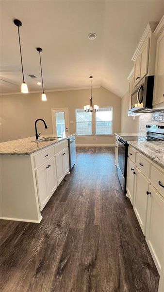 Kitchen with white cabinets, appliances with stainless steel finishes, decorative light fixtures, and sink