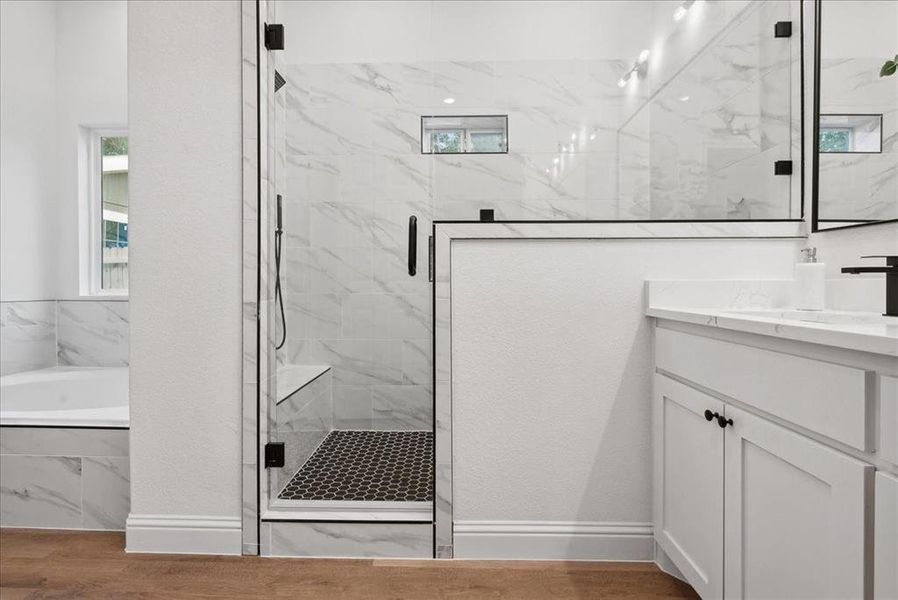 Bathroom featuring hardwood / wood-style floors, rainfall shower heads and bath, and vanity