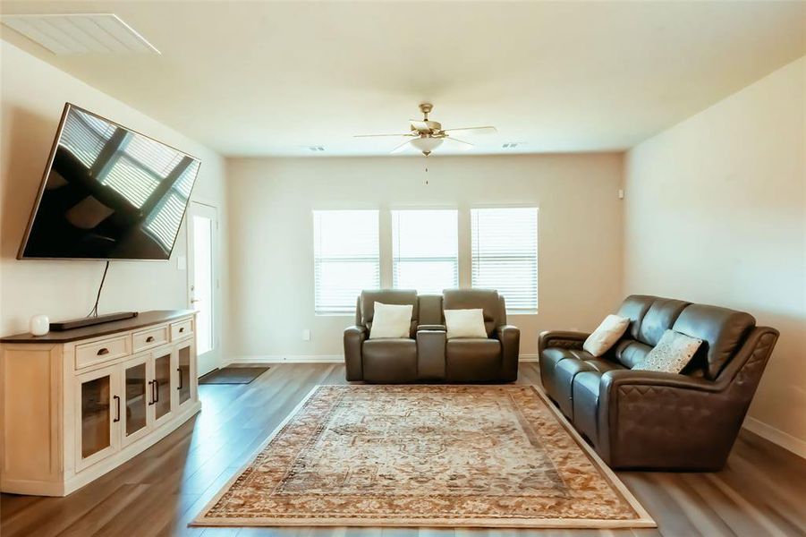 Living room featuring dark wood-type flooring and ceiling fan