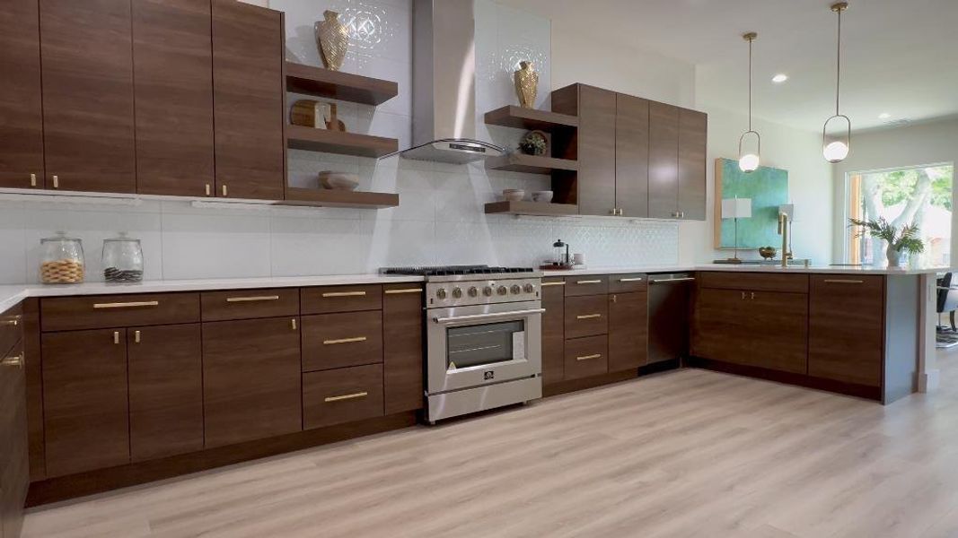 Kitchen featuring appliances with stainless steel finishes, pendant lighting, tasteful backsplash, and light hardwood / wood-style flooring
