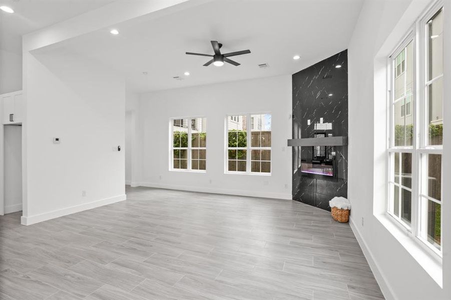 The electric fireplace runs the length of the wall and has a black finish. There is plenty of natural lights with the windows.