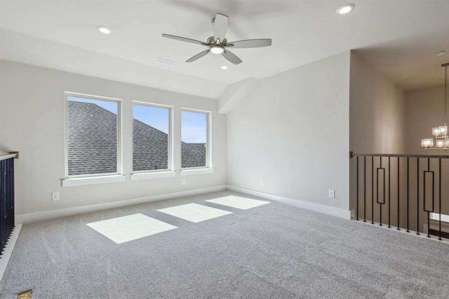 Carpeted empty room with ceiling fan with notable chandelier