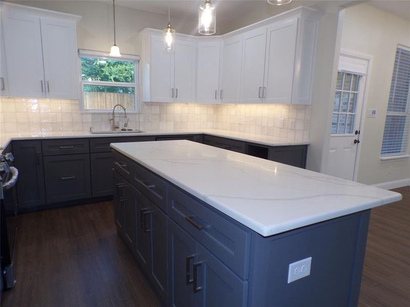 Kitchen with white cabinets, pendant lighting, sink, a center island, and dark hardwood / wood-style flooring