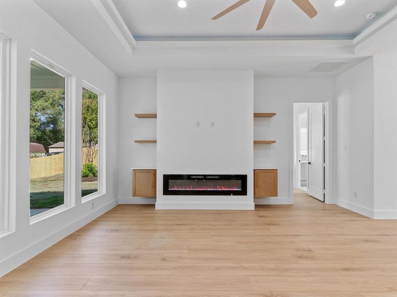 Unfurnished living room featuring ceiling fan, light hardwood / wood-style flooring, plenty of natural light, and built in shelves