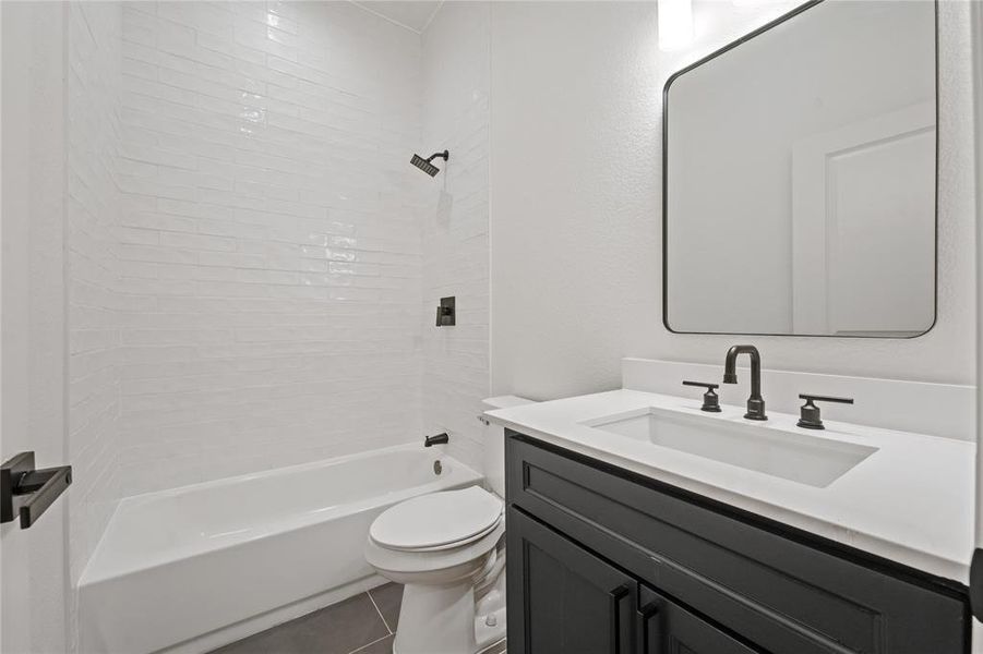 Full bathroom featuring tile flooring, tiled shower / bath, vanity, and toilet