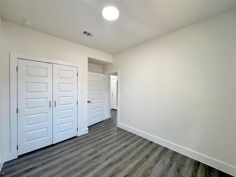 Unfurnished bedroom with dark hardwood / wood-style flooring and a closet