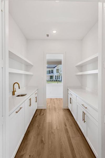 Bar featuring white cabinetry, light hardwood / wood-style flooring, and sink