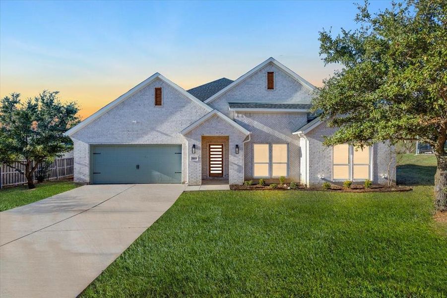 View of front of property with a garage and a yard