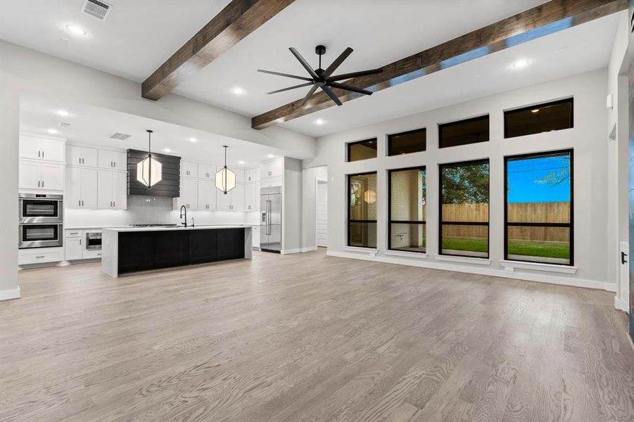 At the core of this residence lies the expansive den, offering views of the outdoor covered patio and the spacious kitchen.