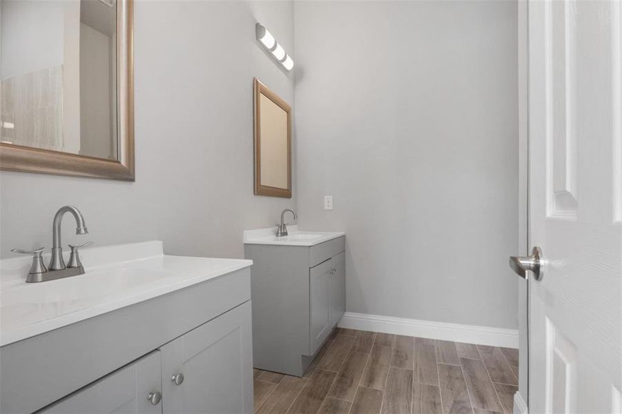Bathroom with dual vanity and wood-type flooring