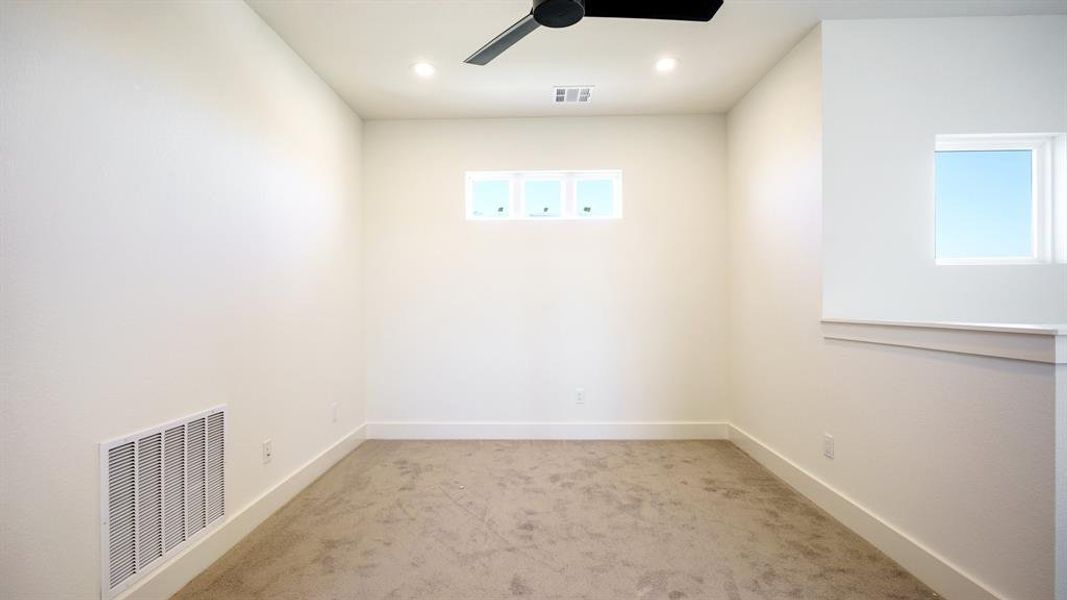 Carpeted spare room featuring ceiling fan