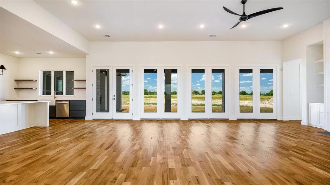 Unfurnished living room with light hardwood / wood-style floors, ceiling fan, and a wealth of natural light