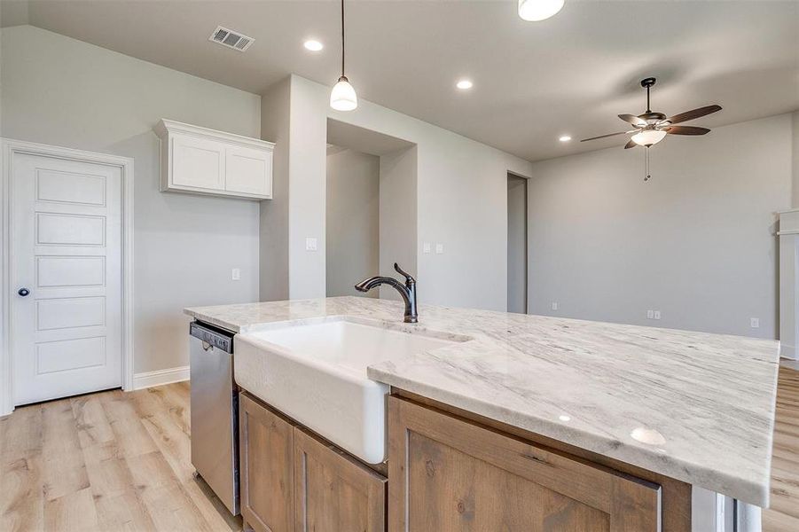 Kitchen featuring light stone counters, hanging light fixtures, light wood-type flooring, white cabinetry, and ceiling fan