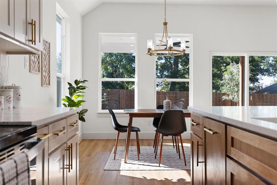 Dining area with an inviting chandelier, light hardwood / wood-style flooring, and vaulted ceiling