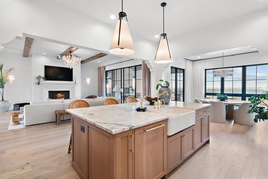 Kitchen featuring beam ceiling, a center island with sink, light hardwood / wood-style floors, hanging light fixtures, and sink