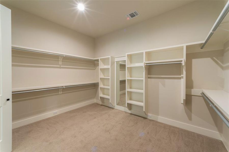 Large primary closet with shelving and full size mirror.