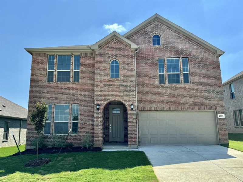 View of front of property featuring a garage and a front lawn