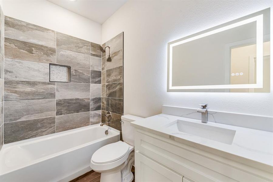 Full bathroom featuring toilet, vanity, and tiled shower / bath