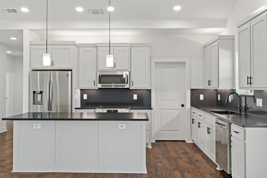 Kitchen featuring white cabinetry, backsplash, dark hardwood / wood-style flooring, hanging light fixtures, and appliances with stainless steel finishes