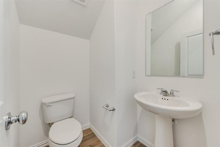 Bathroom featuring vaulted ceiling, toilet, and hardwood / wood-style floors