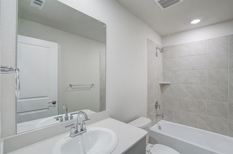 Full bathroom featuring tiled shower / bath, vanity, and toilet