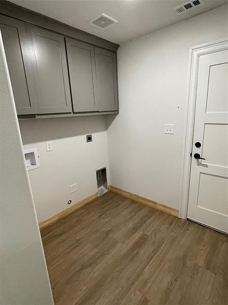 Laundry area featuring hookup for an electric dryer, wood-type flooring, and cabinets