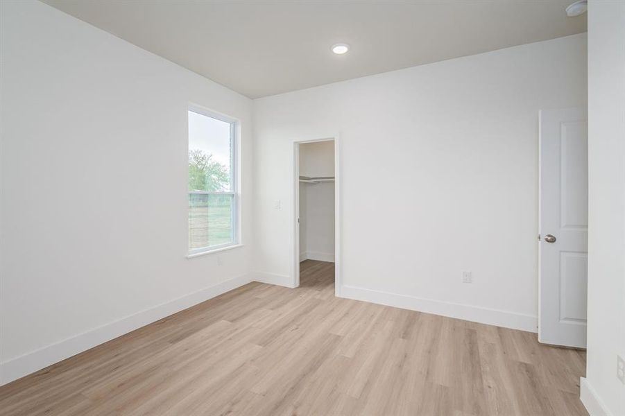 Unfurnished bedroom featuring light wood-type flooring, a closet, and a spacious closet